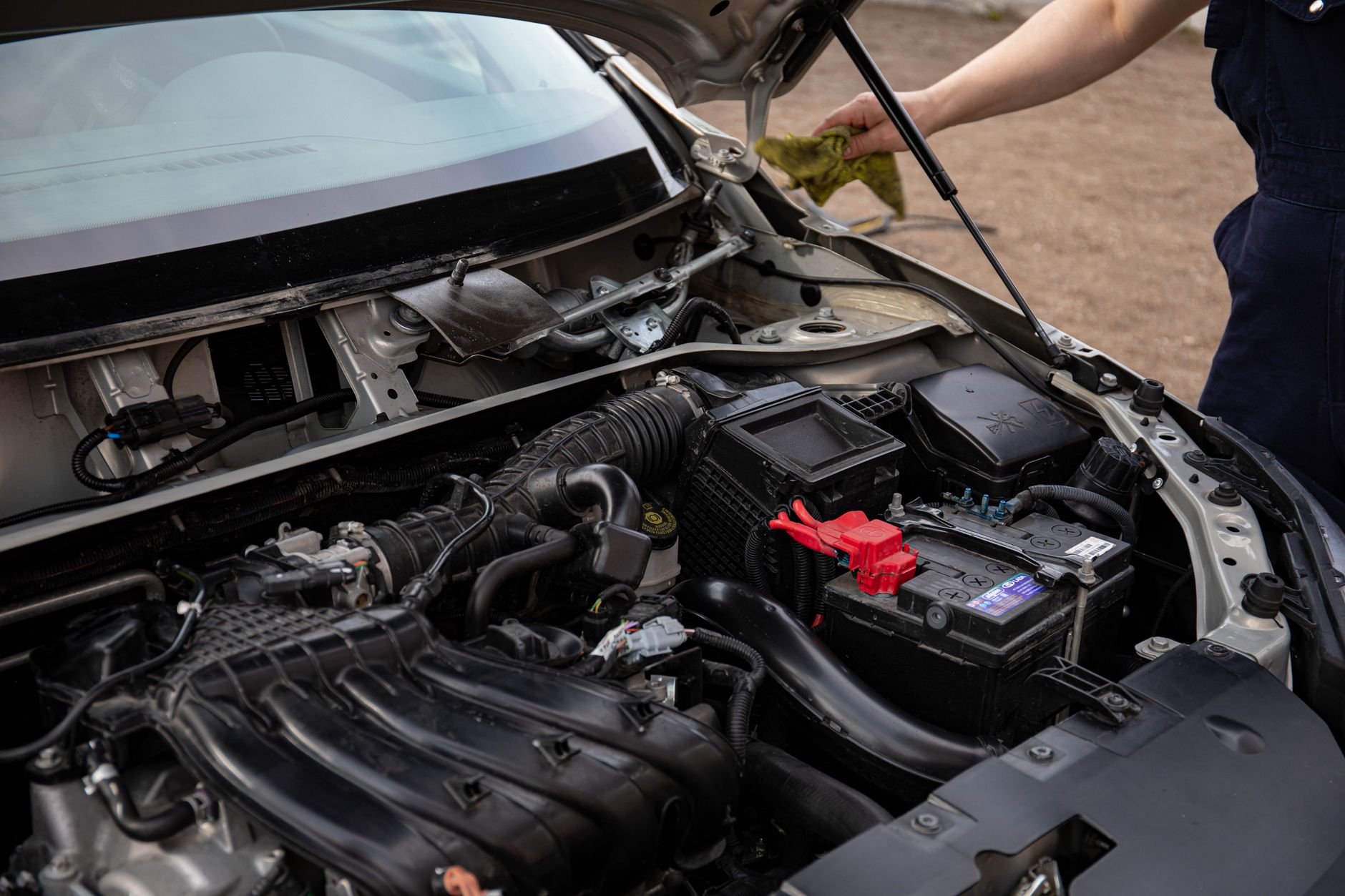 Mechanic inspecting car engine bay and battery during routine maintenance